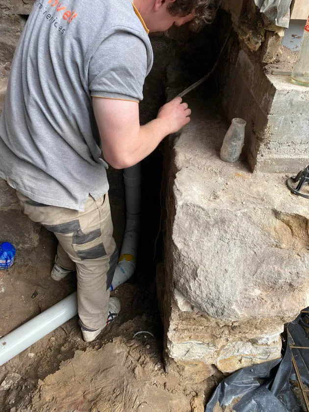 Working a pipe repair beside an old sandstone footing